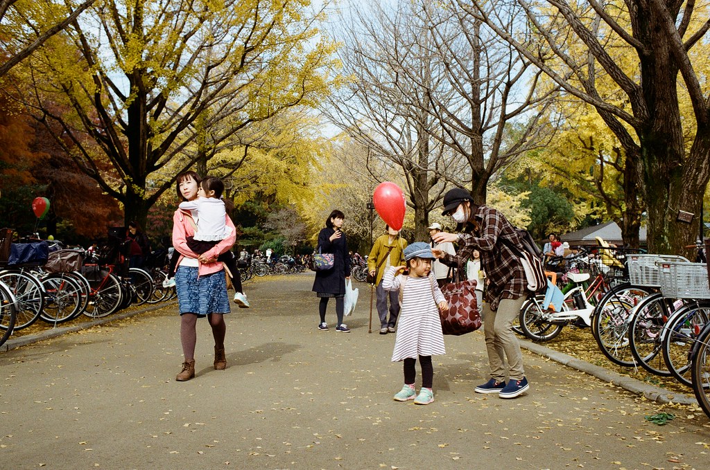 光が丘公園 Tokyo, Japan / Kodak ColorPlus / Nikon FM2 這個畫面也很可愛，是一個小妹妹背包上的氣球纏住她了，但不知道為什麼她媽媽一直在旁邊笑不救她女兒，她女兒就一直快速轉來轉去！  也是很可愛的畫面！  光丘這裡是新社區，看得到很多小朋友與家庭一起出來逛逛的畫面！  很溫馨，尤其是在天氣開始轉涼的季節。  Nikon FM2 Nikon AI AF Nikkor 35mm F/2D Kodak ColorPlus ISO200 7412-0036 2016-11-20 光が丘公園 Tokyo, Japan  Photo by Toomore