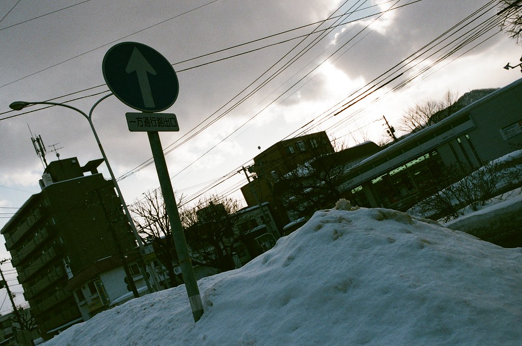 學園前 札幌 北海道 Sapporo, Japan / AGFA VISTAPlus / Nikon FM2 2016/01/31 住的地方在學園前站（gakuenmae），把行李安置好後在附近走走，但那時候南北方向搞錯了，本來想要走回大通公園，結果越走越南，之好走到下一站平岸往回搭。  一路上就隨意走走拍拍，一直觀察路上的積雪，沒有看過，所以很好奇。雪自然的堆疊起來後的表面很光滑，輕輕一碰就凹陷下去。  那時候拍到一半相機沒電，在寒冷的情況下，手不聽使喚的完成換電池的挑戰！  Nikon FM2 Nikon AI AF Nikkor 35mm F/2D AGFA VISTAPlus ISO400 8264-0030 Photo by Toomore