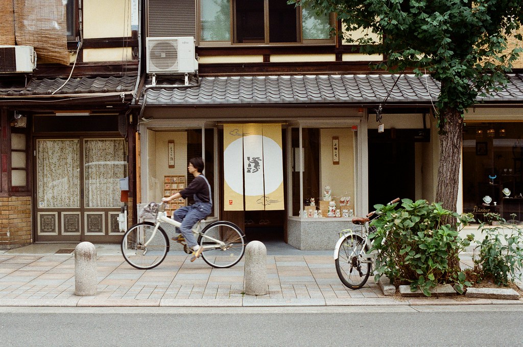 寺町通 京都 Kyoto / Kodak ColorPlus / Nikon FM2 2015/09/27 整理照片的時候發現我那時候在寺町通也拍了滿多街上騎腳踏車的路人，這裡街道不寬，兩旁都有看起來好像是歷史很久的店家，店家門面都很有特色。  我想起來了，那時候拍照有規定自己畫面中一定要有當地人入鏡，因為之前拍太多空無一人的畫面，畫面太過空寂。  Nikon FM2 Nikon AI Nikkor 50mm f/1.4S Kodak ColorPlus ISO200 0985-0033 Photo by Toomore